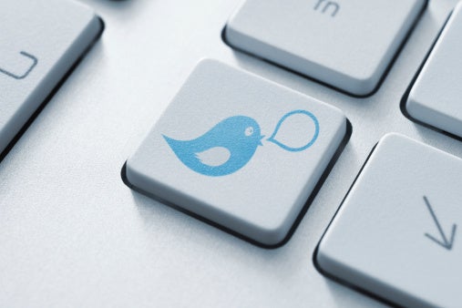 A close-up of a keyboard, one key of which has the blue Twitter bird logo on it.